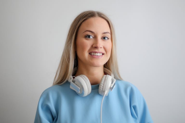 Portrait of a happy woman with headphones, wearing a blue top, smiling warmly.